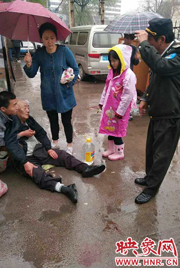 女孩為倒地老人撐傘。