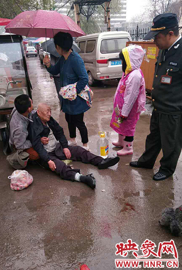 女孩為倒地老人撐傘。