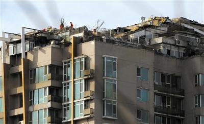 　　昨日，身穿橘黃色馬甲的工作人員在人濟山莊樓頂拆除違章建筑。新京報記者 吳江 攝