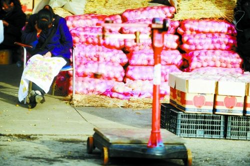 水果批發(fā)市場(chǎng)內(nèi)，沒有客戶時(shí)，商戶在繡十字繡