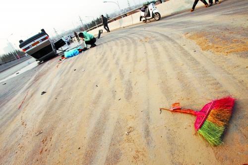 被撞的環(huán)衛(wèi)工躺在地上，身上蓋著藍(lán)色布?jí)K，現(xiàn)場除散落的汽車碎片外，還留有被撞斷的掃帚。