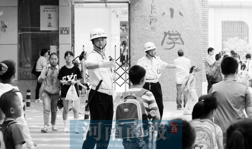 伊河路小學(xué)門(mén)口，兩名巡防隊(duì)員護(hù)送學(xué)生過(guò)馬路