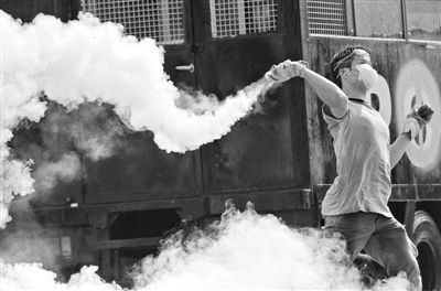 12月2日，泰國(guó)曼谷，一名反政府示威者在總理府附近向負(fù)責(zé)執(zhí)勤的警察投擲催淚彈。英拉請(qǐng)求示威者不要再試圖占領(lǐng)政府工作部門，不要逼迫政府工作人員選邊站。