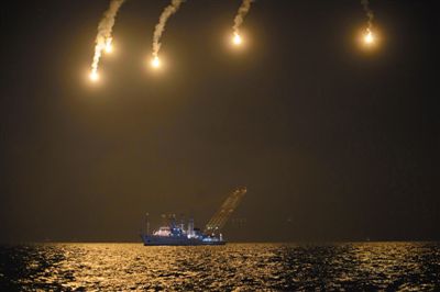 22日，搜救人員在照明彈的光亮下連夜搜救。