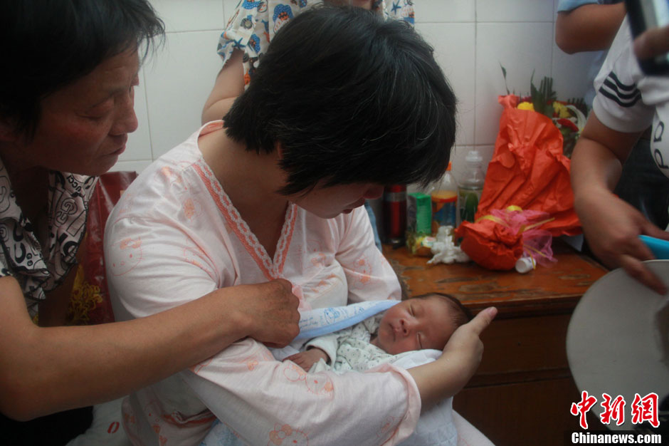 圖為久別重逢，獲救嬰兒母親悉心撫摸愛子。張一辰 攝