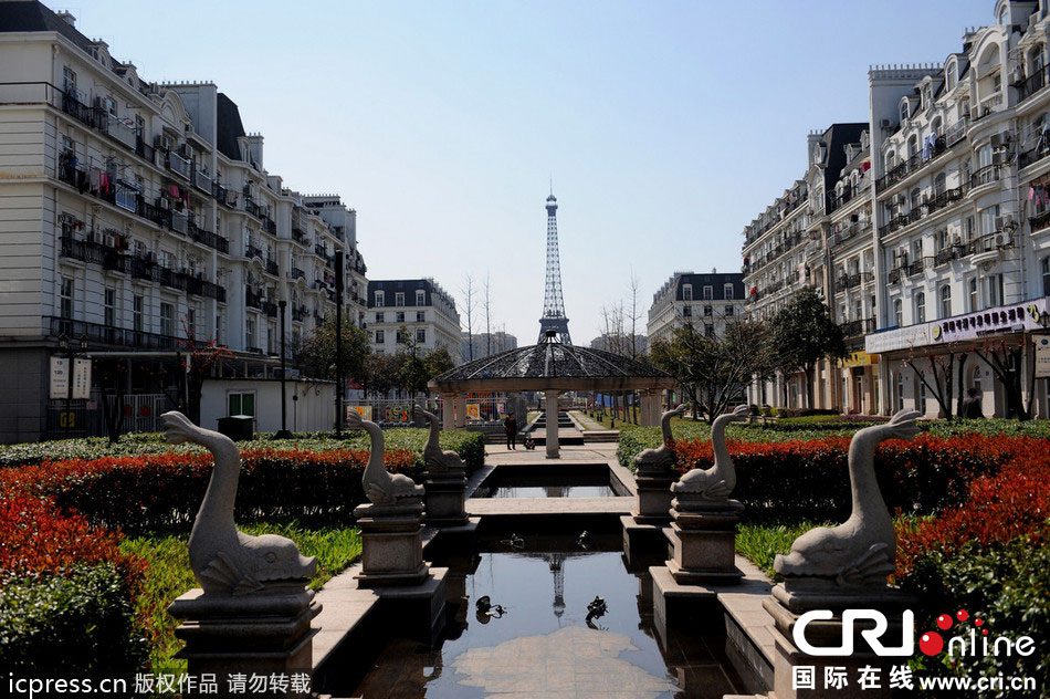 　2014年3月21日，杭州天都城，農(nóng)民在山寨埃菲爾鐵塔下耕作。圖片來源：東方IC