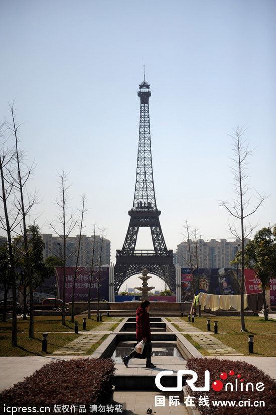 　2014年3月21日，杭州天都城，農(nóng)民在山寨埃菲爾鐵塔下耕作。圖片來源：東方IC