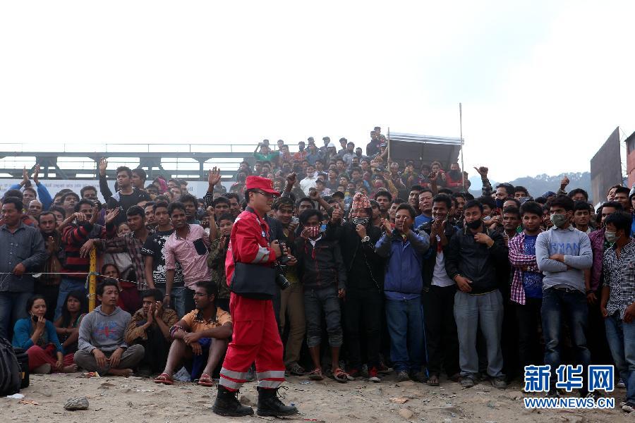 圍觀的尼泊爾民眾在中國(guó)國(guó)際救援隊(duì)成功搜救出幸存者后向搜救隊(duì)員歡呼致意。
