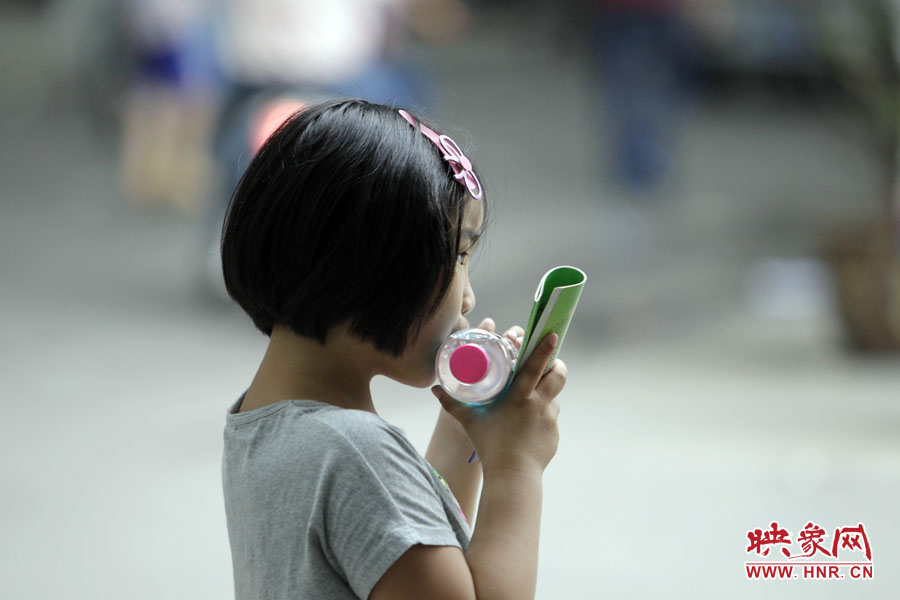 6月7日，鄭州回中考點(diǎn)，一名孩子拿著一瓶礦泉水，等待哥哥走出考場