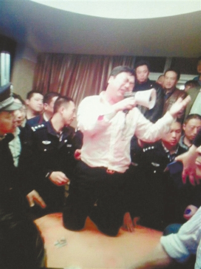 　4月19日，泰州市濱江工業(yè)園區(qū)管委會(huì)招待中心，一男子跪在酒桌上喊話求饒。李根 攝