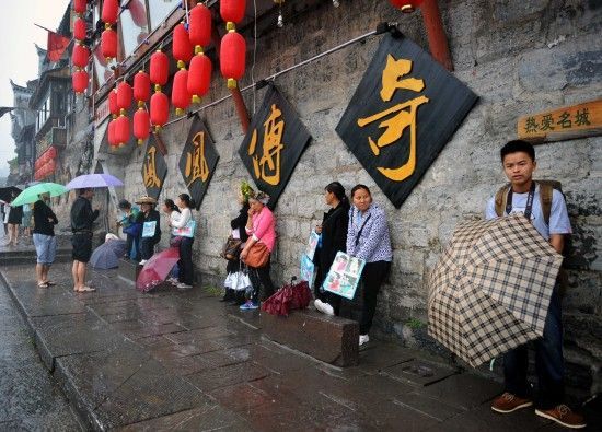 　4月29日上午11時20分，一些游客和古城當?shù)氐木用穸阍谝粋€酒吧的屋檐下避雨。這些當?shù)鼐用褚詾橛慰团恼罩\生，一場降雨讓他們的生意更加清淡。