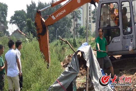 陳寶成手持自制刀斧守在挖掘機旁阻止便衣民警靠前。駕駛室內，張朋珂正向受害人郭曉剛身上澆汽油。（視頻截圖）