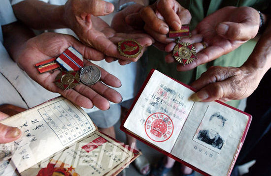 幾位志愿軍老兵展示自己的立功證、傷殘軍人證與勛章