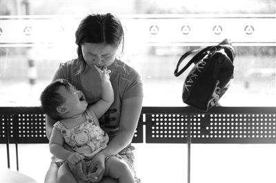 昨日，肯德基京廣中心店門口，姜女士提起跟養(yǎng)父母的關(guān)系時(shí)落淚，懷中9個(gè)月的女兒笑著跟她玩。新京報(bào)記者 薛珺 攝