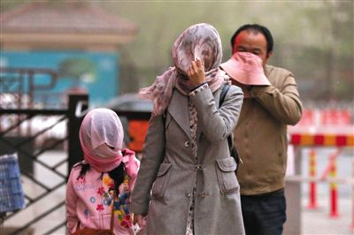 昨日下午，朝陽區(qū)豆各莊，行人將紗巾裹在頭上防沙塵。