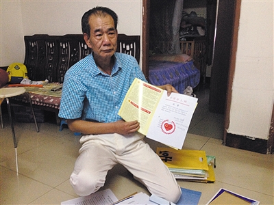 翻出一家網(wǎng)站贈予的“中國好人”證書，區(qū)少坤單膝跪在地上，“你看，我是中國好人啊?！?范春旭 攝