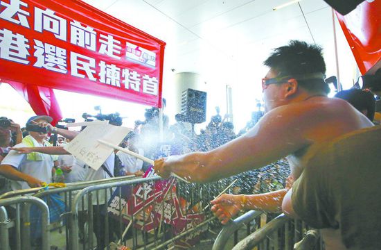 17日，在香港立法會外，一名反對政改的男子向支持派人群投擲標(biāo)牌。