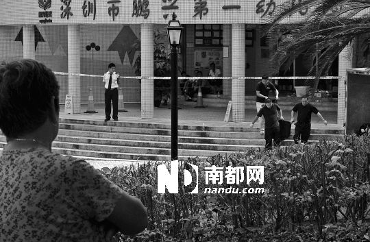 →7月19日，鵬興花園第一幼兒園門前，民警在現(xiàn)場(chǎng)進(jìn)行完勘查取證后，園長(zhǎng)和保安的尸體被運(yùn)走。南都記者 徐文閣 攝