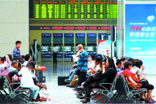 候車大廳溫度很高，一名乘客一手扇風、一手擦汗