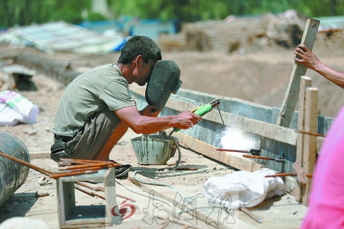 　正午陽光下，工地上的焊接工人還在認(rèn)真工作。
