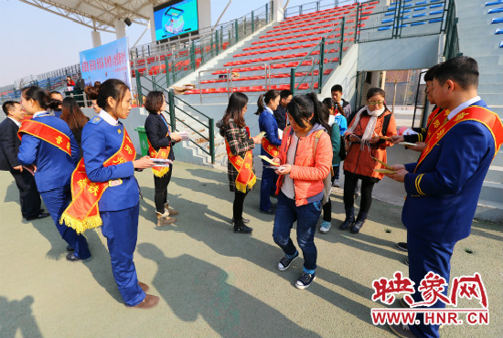 活動(dòng)現(xiàn)場工作人員給同學(xué)們發(fā)放宣傳冊、環(huán)保袋。