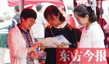 家長和孩子在高招咨詢會上咨詢學校信息 家長和孩子在高招咨詢會上咨詢學校信息