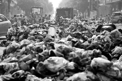 垃圾堆滿整個路口，環(huán)衛(wèi)工人們正在清理