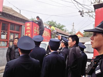 昨日下午,東城區(qū)工商、城管、公安等部門,對雍和宮附近的預(yù)測中心進(jìn)行清理整頓,站在車頂?shù)膬擅と苏鸪患摇邦A(yù)測中心”的招牌。因雍和宮、白云觀等文化景點(diǎn)外聚集大量算命先生,被媒體稱為“算命一條街”。本版攝影/新京報記者 李寧 攝