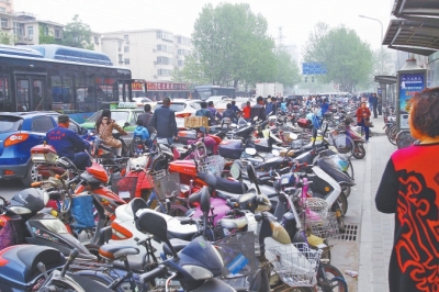 省人民醫(yī)院北門，路邊的公交站牌處停滿非機(jī)動車，上、下客只能在快車道上。