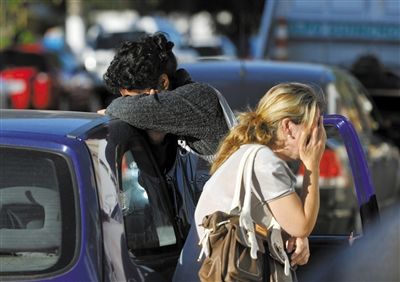 27日，遇難者親友在火災現(xiàn)場旁哭泣。