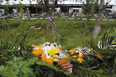 昨日，吉林省德惠市吉林寶源豐禽業(yè)有限公司燃燒事故現(xiàn)場警戒線外，遇難者家屬在路邊擺放了花圈祭奠逝去的親人。吳江 攝