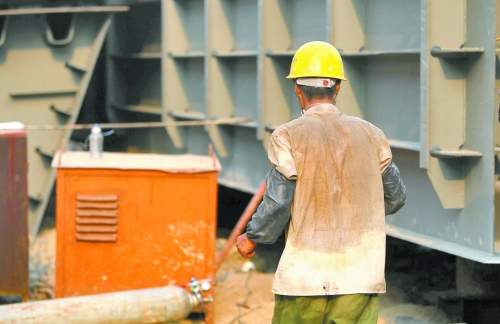 工地上，一建筑工人的衣服被汗水浸透。