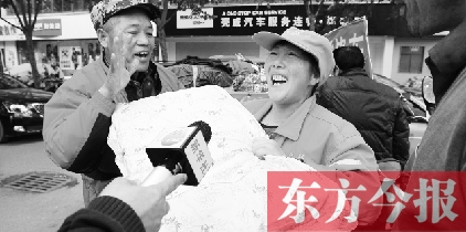 一名環(huán)衛(wèi)工師傅高興地從孫德坤手里接過(guò)棉被