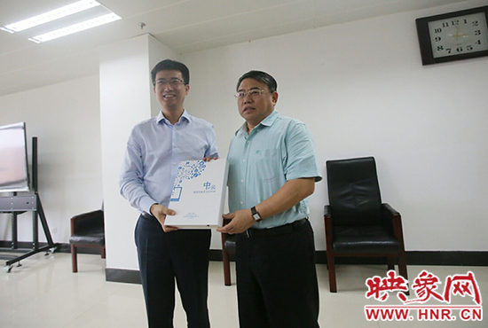 阿里云計算總裁胡曉明向河南省新聞出版廣電局局長朱夏炎遞交《中原云平臺交付手冊》。