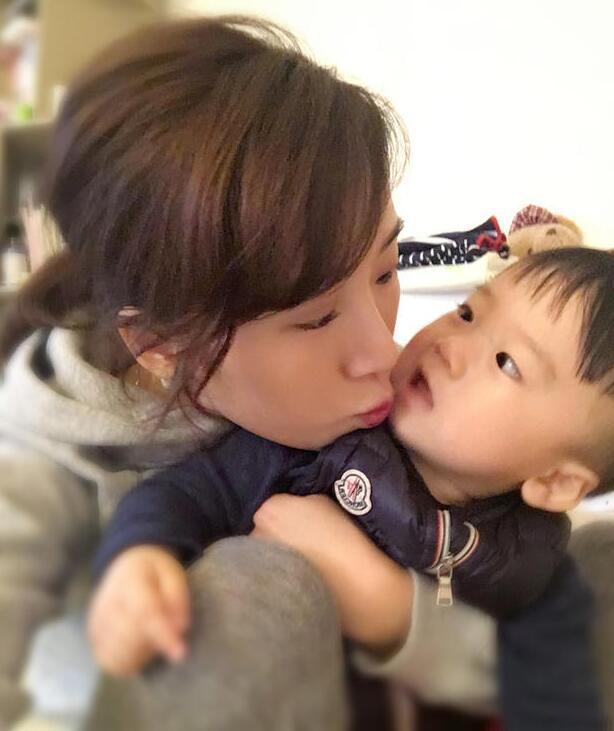 照片中李念狂吻兒子，小寶貝自顧自地玩著。