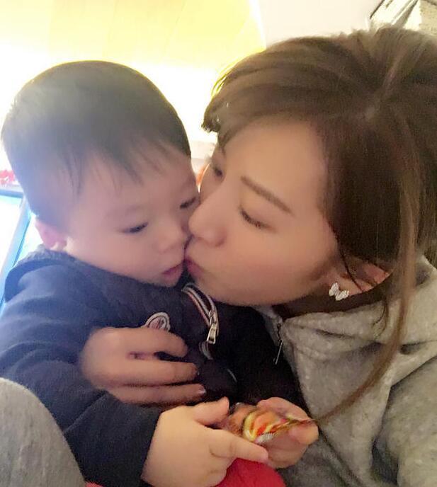 照片中李念狂吻兒子，小寶貝自顧自地玩著。