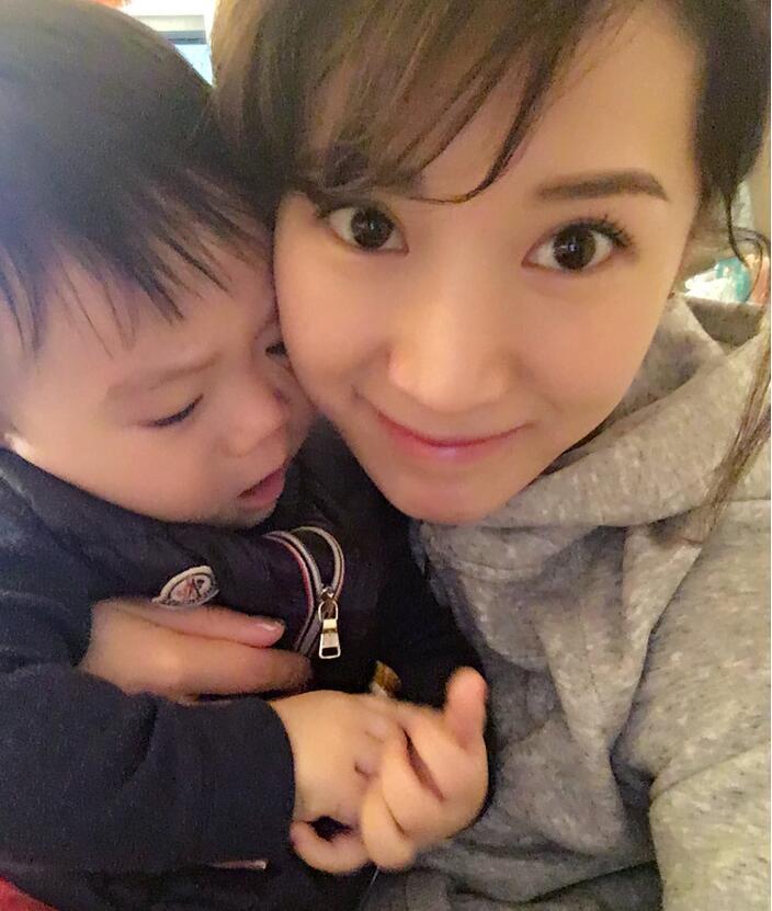 照片中李念狂吻兒子，小寶貝自顧自地玩著。