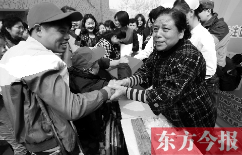 昨日，鄭大四附院的大樓前，“面人鄭”鄭玉芬（右）向前來捐款的殘疾人表示感謝