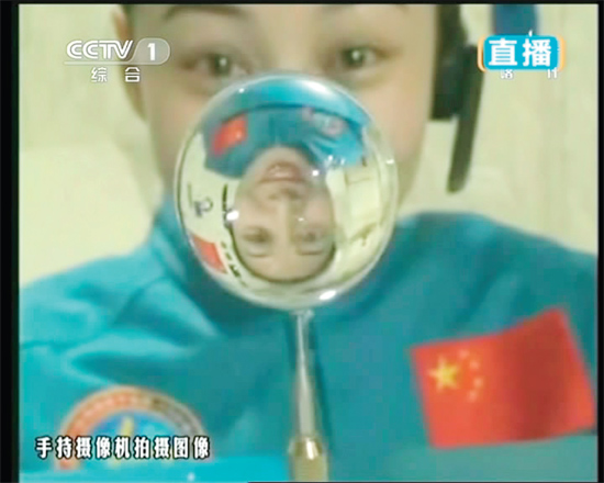 王亞平的倒影出現(xiàn)在水球中。新華社發(fā)（視頻截圖）