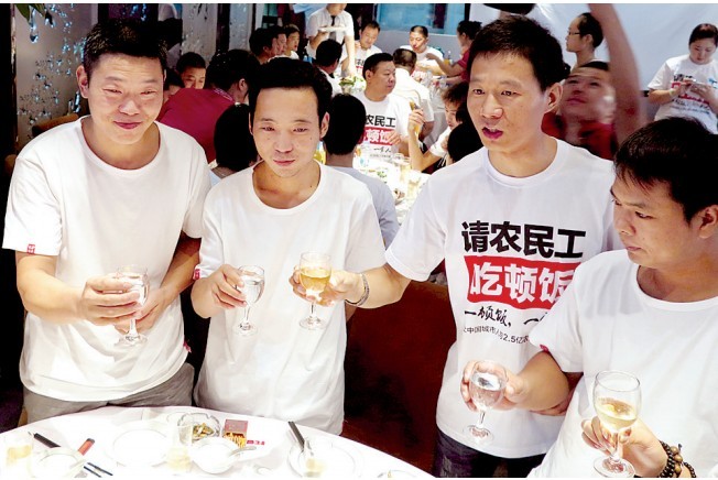 活動發(fā)起人張楠（右二）給農(nóng)民工敬酒。