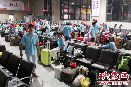 大學(xué)生志愿者在火車站候車室內(nèi)整裝待發(fā)。