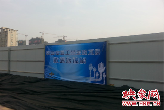 道路南側(cè)圍起了白色的圍擋，墻上標(biāo)示著“因地鐵施工帶來(lái)的不便敬請(qǐng)您諒解”的提示牌。