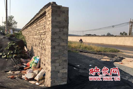 一墻之隔，一邊是道路，一邊是垃圾和荒草，市民質(zhì)疑其為遮羞墻。