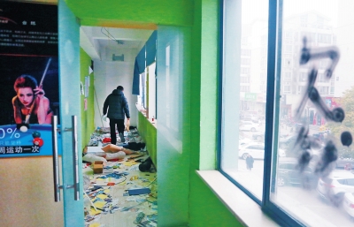 　健身會(huì)所地上一片狼藉，玻璃上噴著黑色“欠錢”二字。