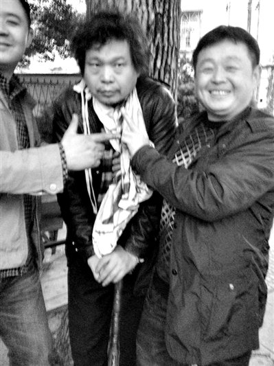 兩名接訪人員與患有癌癥的訪民段新德合影時(shí)，面帶笑容擺出勝利的手勢。