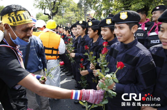2013年12月03日,曼谷總理府與曼谷警署允許反政府示威民眾進(jìn)入,雙方進(jìn)入暫時(shí)“停戰(zhàn)”狀態(tài)迎接泰王生日。曼谷警察總署,女警們手持鮮花送給反政府示威民眾。圖片來源:Manish Swarup/東方IC