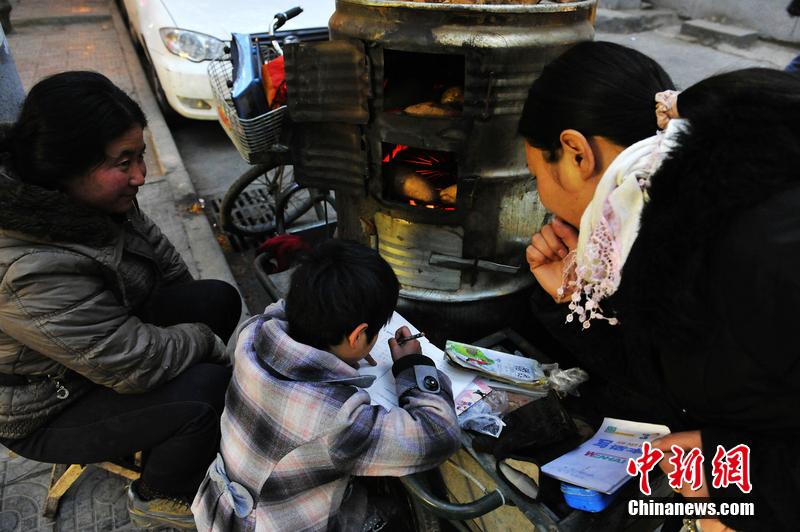 男孩西安路燈下寫(xiě)作業(yè) 媽媽邊賣(mài)紅薯邊輔導(dǎo)