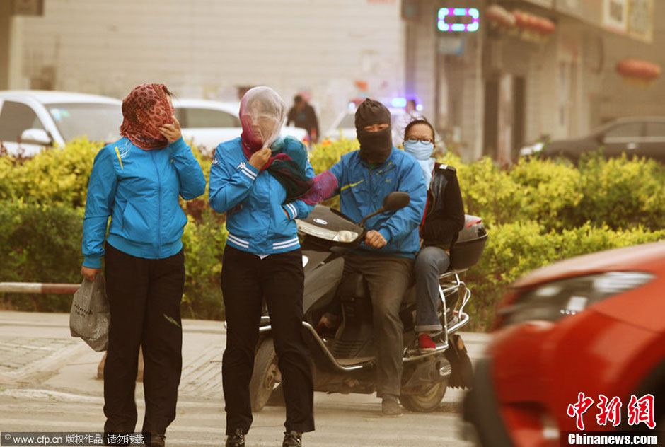 2014年04月23日，新疆維吾爾自治區(qū)吐魯番地區(qū)，市民戴著口罩行走在大風(fēng)沙塵中的吐魯番市街頭。