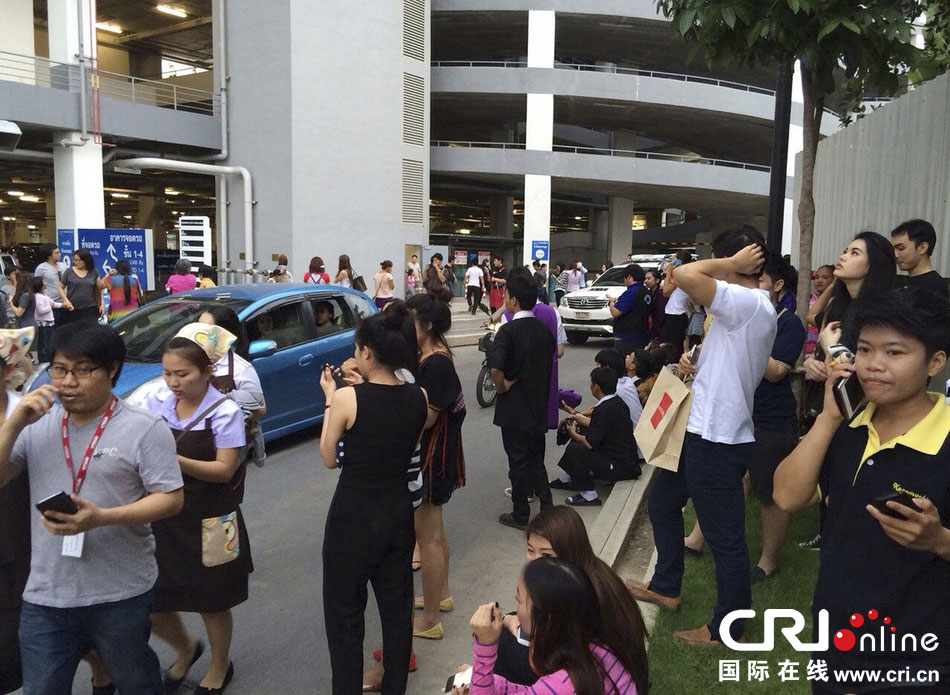 當(dāng)?shù)貢r(shí)間2014年5月5日，泰國(guó)清萊，工人們站在一棟大樓外避難。