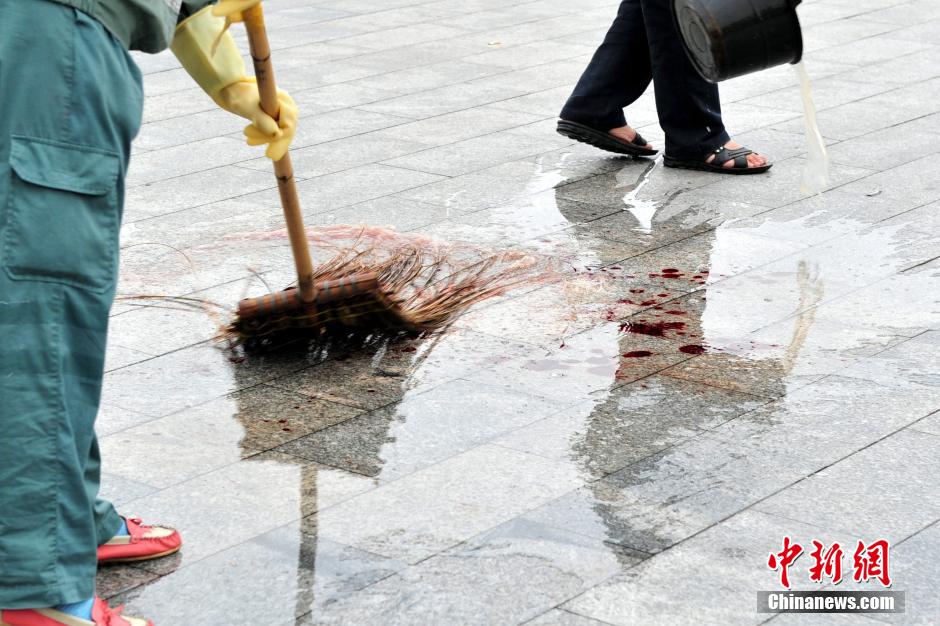 圖為環(huán)衛(wèi)工人在清理案發(fā)地點的血跡。